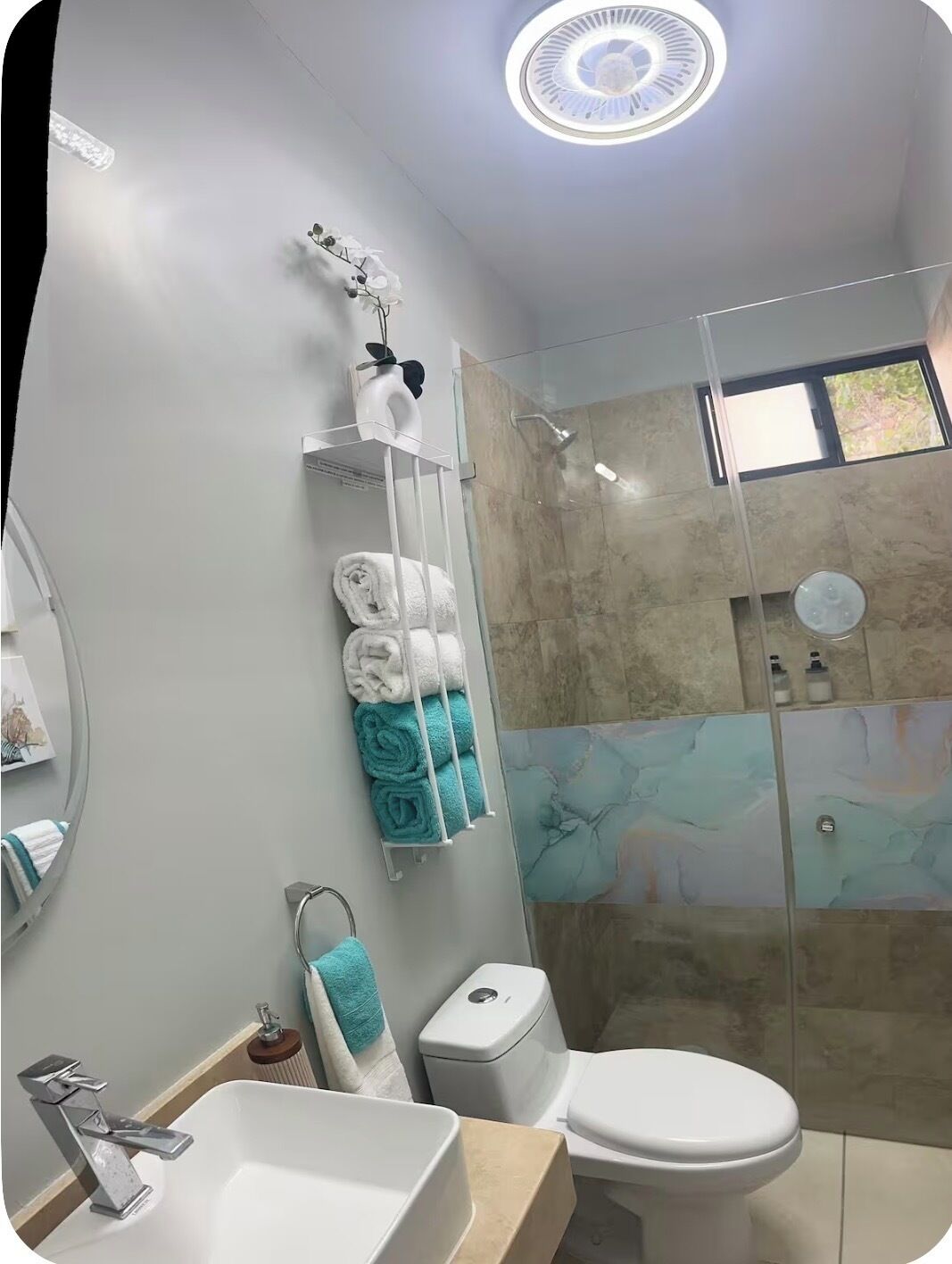 Une salle de bain moderne avec une douche à parois de verre, des toilettes blanches et un lavabo doté d’un robinet chromé.