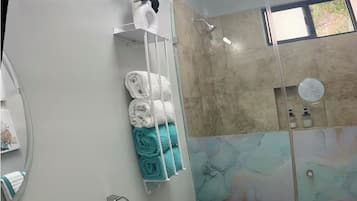 Une salle de bain moderne avec une douche à parois de verre, des toilettes blanches et un lavabo doté d’un robinet chromé.