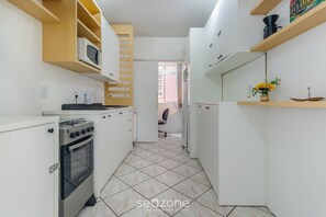 A compact kitchen with white cabinets, a microwave, a stove, and a refrigerator. - Apartment With 2 Bedrooms in Floripa Opt0101 (Florianópolis)
