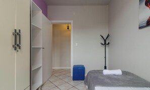 A bedroom with a bed, a coat rack, a blue suitcase, and a wardrobe. - Apartment With 2 Bedrooms in Floripa Opt0101 (Florianópolis)