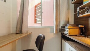 Cocina compacta con ventana, una silla y una encimera con un radio.