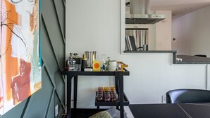 Una cucina moderna con un piano di lavoro nero, una cappa aspirante in acciaio inossidabile e uno specchio a parete che riflette l'ambiente.