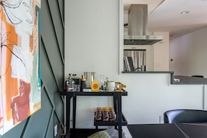 Una cocina moderna con encimera negra, campana extractora de acero inoxidable y un espejo en la pared que refleja la cocina.