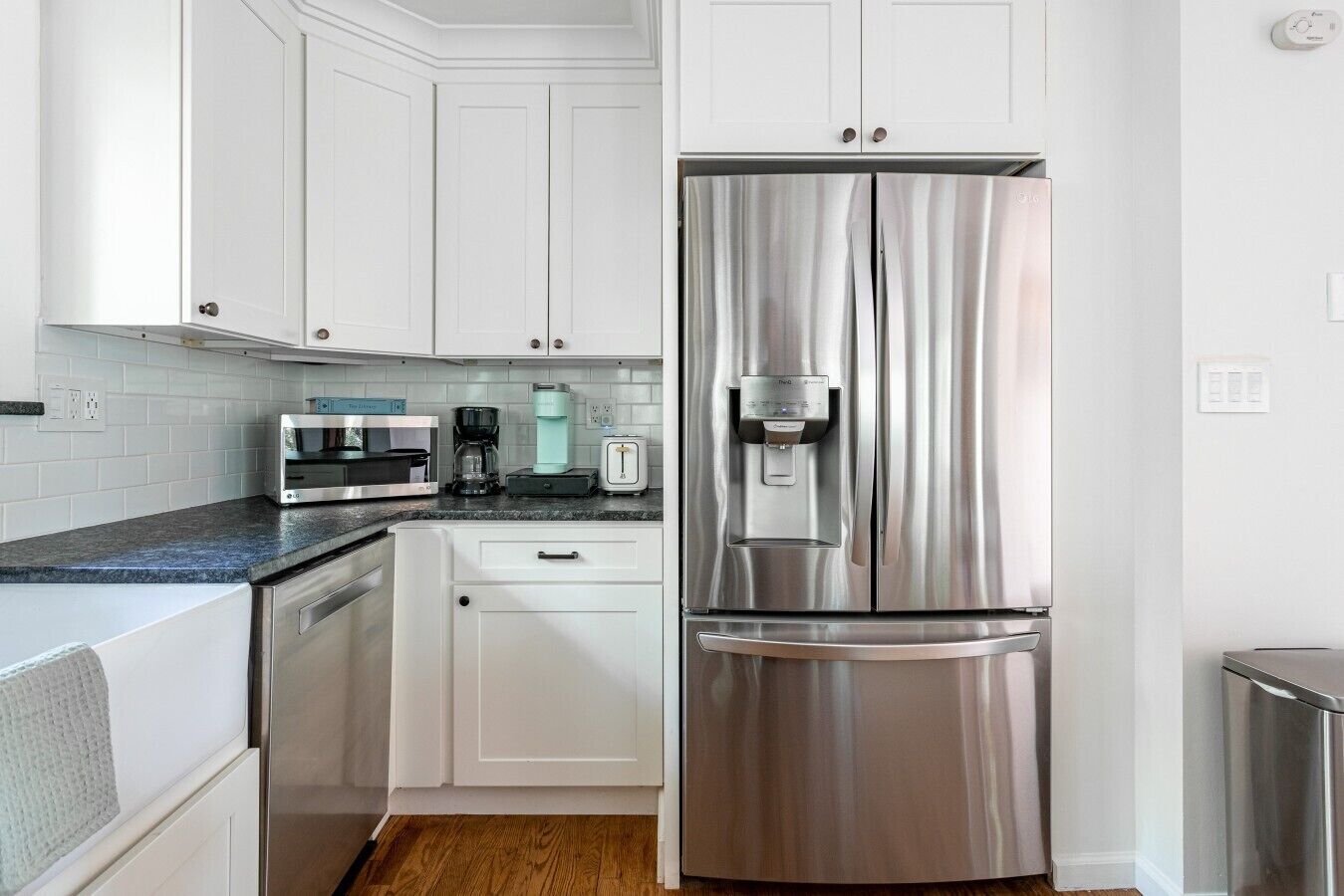 A modern kitchen with white cabinetry, stainless steel appliances, and a built-in water dispenser.