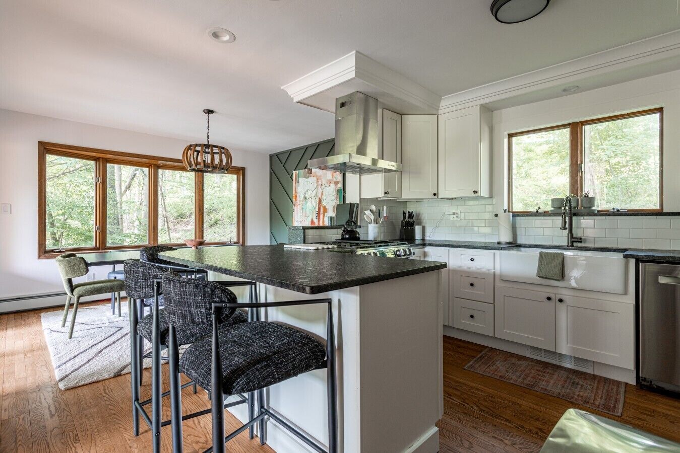 A modern kitchen with a central island, white cabinetry, and large windows.