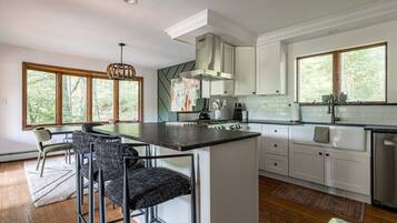 A modern kitchen with a central island, white cabinetry, and large windows.