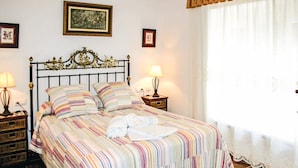 A neatly made bed with a striped bedspread, two bedside lamps, and framed artwork on the walls. - Amazing home in Benalub Casas Viejas (Benalub Casas Viejas)