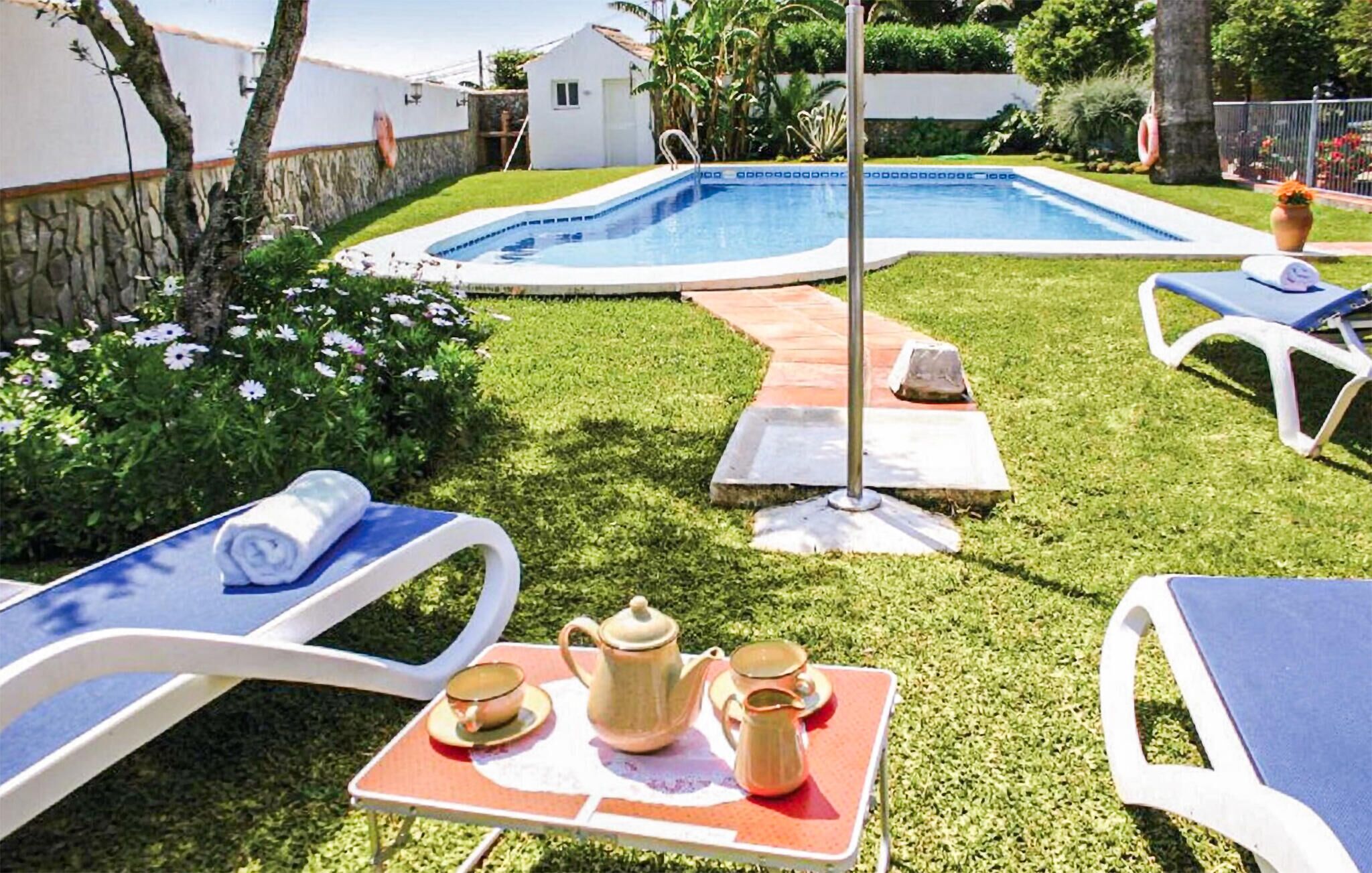 Un patio trasero con piscina, sillas de descanso y una mesa con tetera y tazas.