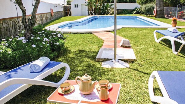 A backyard with a swimming pool, lounge chairs, and a table with a teapot and cups. - Amazing home in Benalub Casas Viejas (Benalub Casas Viejas)