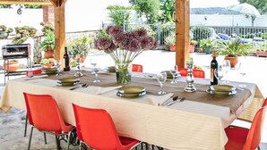 An outdoor dining area with a table set for four, surrounded by red chairs, and a view of the sea in the background. - Amazing home in Benalub Casas Viejas (Benalub Casas Viejas)