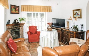 A living room with leather sofas, a red armchair, a fireplace, a television, and various decorative items. - Amazing home in Benalub Casas Viejas (Benalub Casas Viejas)