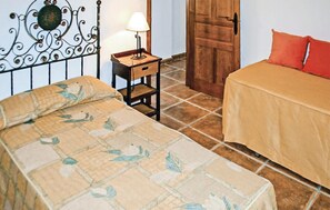Ein Schlafzimmer mit einem Bett, einem Nachttisch, einer Lampe, einer Holztür und einem roten Kissen.
