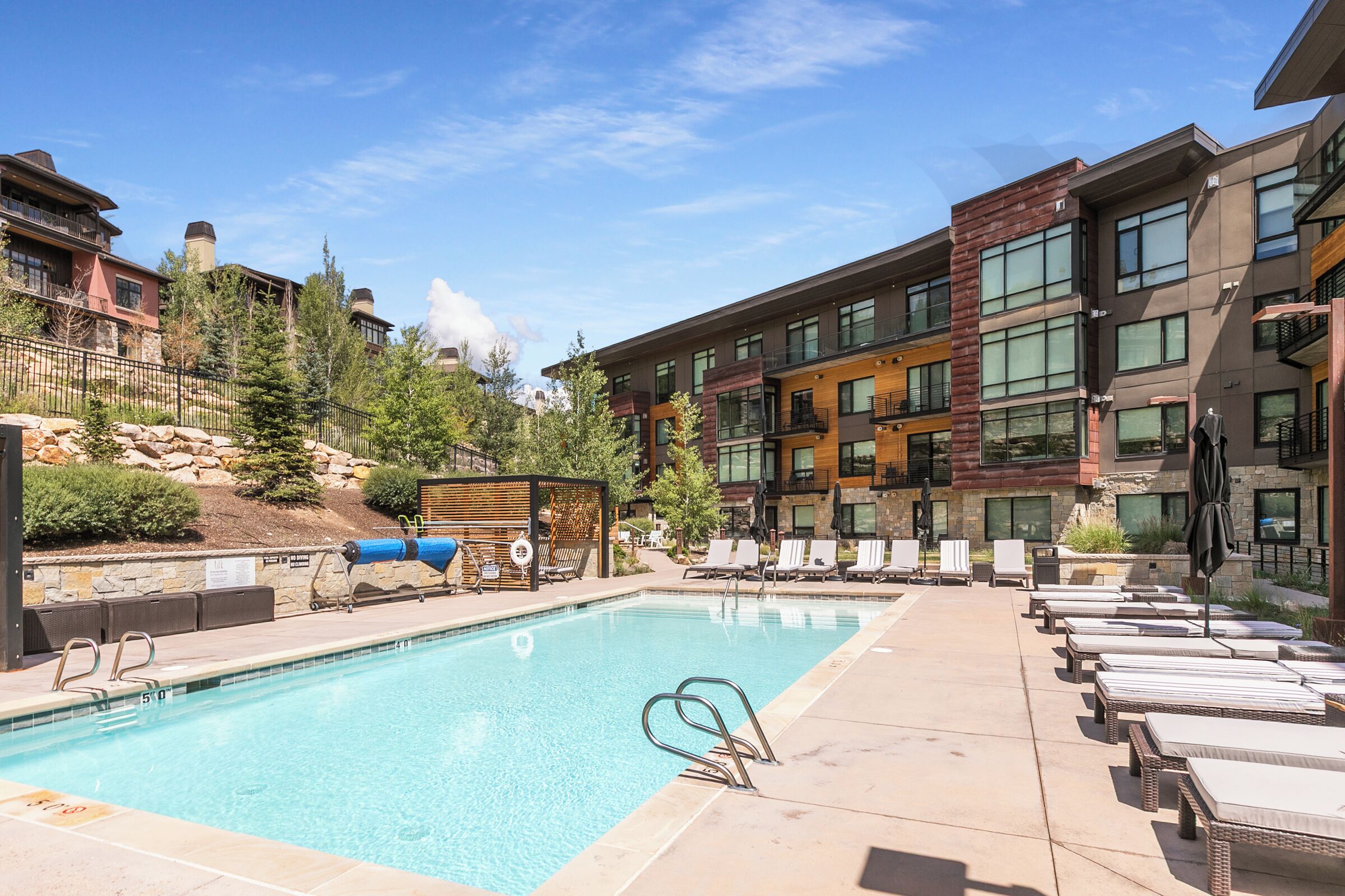 A swimming pool with lounge chairs and a view of modern buildings.