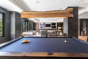 A pool table with balls, a sofa, and a television in a modern room with a large wooden beam ceiling. - True Ski In /Out Lift 2 BD Epic Views, Amazing Amenities; Steps to Gondola (Park City)