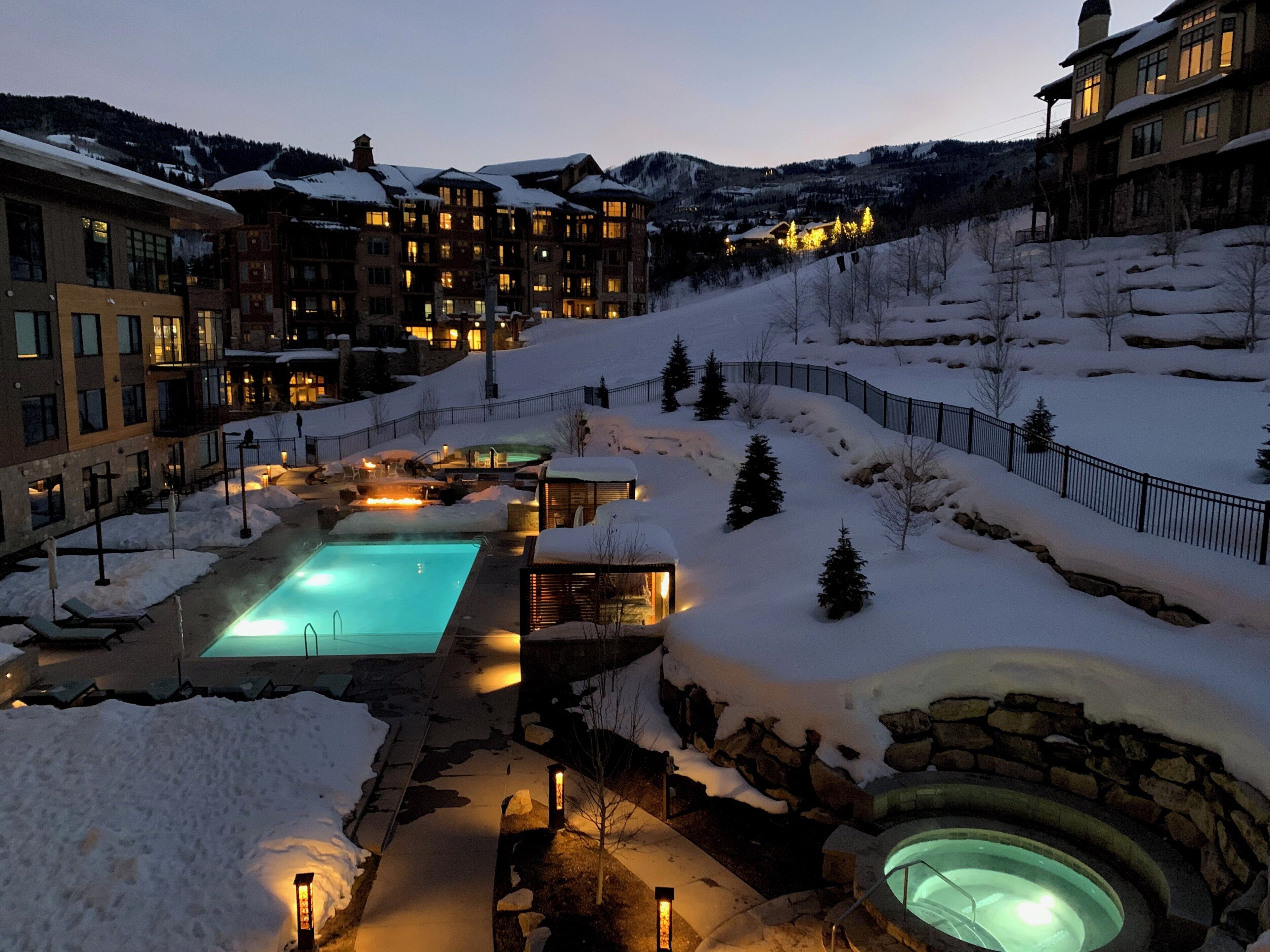 A resort with a swimming pool, hot tubs, and snow-covered grounds.