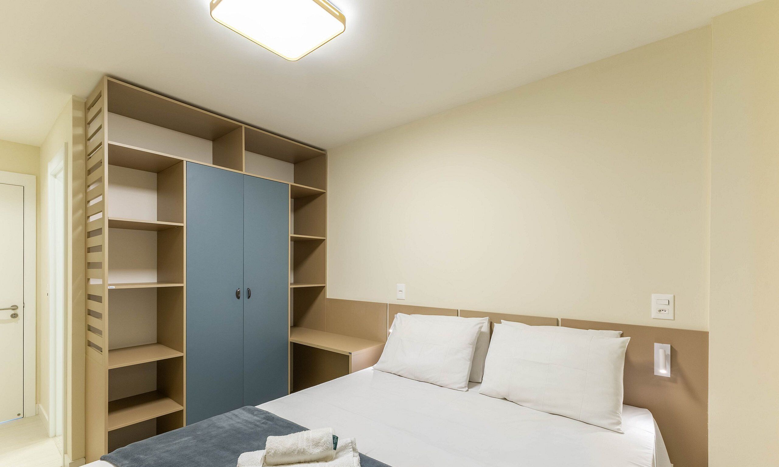 A bedroom with a bed, a wardrobe, and a bedside table.