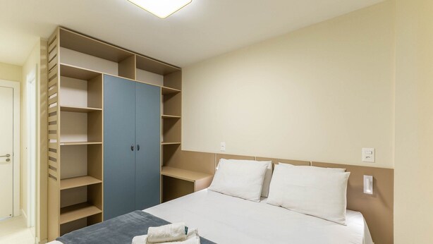 A bedroom with a bed, a wardrobe, and a bedside table. - Ap in Cond w/ Pool Just Steps From the sea Pet0011 (Ilhéus)