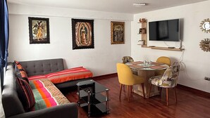 A modern living room with a sofa, a coffee table, a dining table with chairs, and a flat-screen TV mounted on the wall. - Beautiful 2-bedroom apartment perfect for a relaxing getaway. (Wanchaq)
