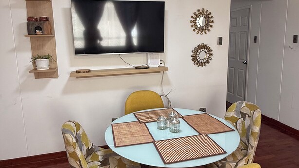 A dining area with a round table, chairs, a flat-screen TV, and decorative wall items. - Beautiful 2-bedroom apartment perfect for a relaxing getaway. (Wanchaq)