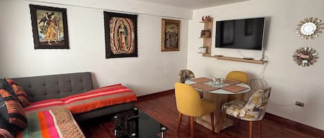 A living room with a sofa, a coffee table, and a dining area with chairs and a table.