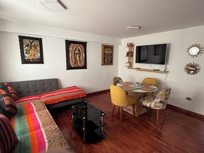 Uma sala de estar com sofá, mesa de centro e área de jantar com cadeiras e mesa.