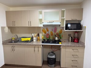 A compact kitchen with a gas stove, microwave, and a trash bin. - Beautiful 2-bedroom apartment perfect for a relaxing getaway. (Wanchaq)