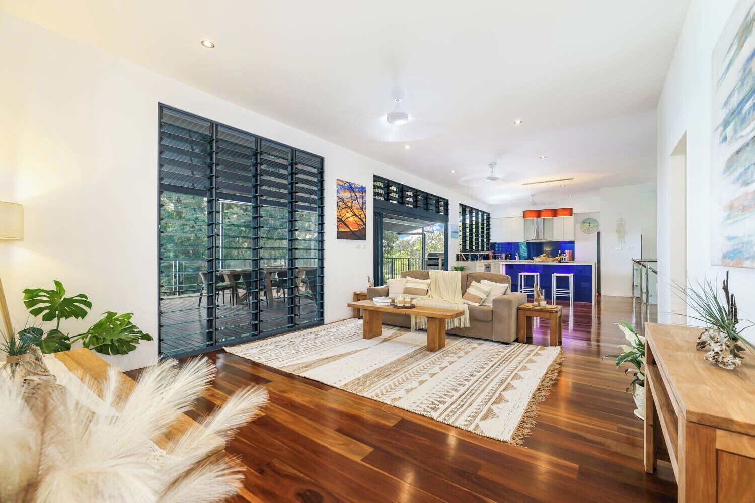 A modern living room with a sofa, coffee table, and a view of the outdoors through large glass doors.