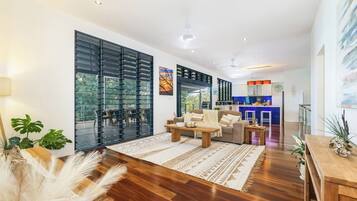 A modern living room with a sofa, coffee table, and a view of the outdoors through large glass doors.
