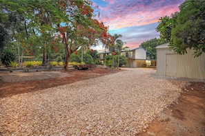 A gravel driveway leading to a modern two-story building with a covered patio area.