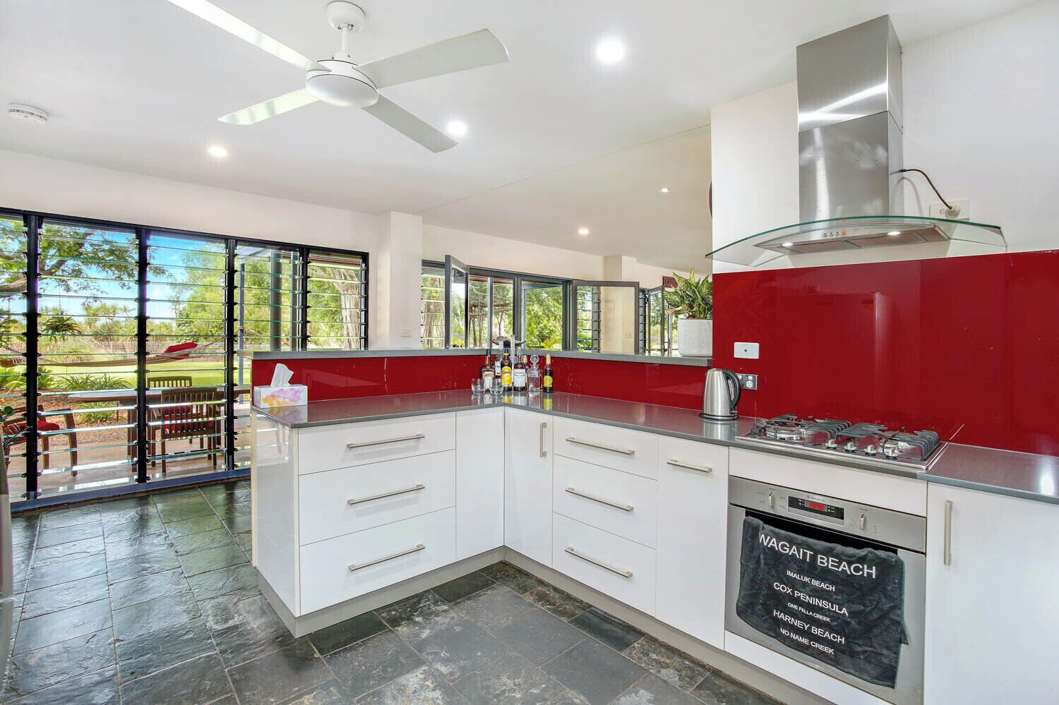 A modern kitchen with a gas stove, white cabinets, and a glass backsplash.