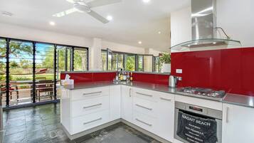 A modern kitchen with a gas stove, white cabinets, and a glass backsplash.