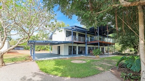 A two-story house with a covered patio and a lawn.