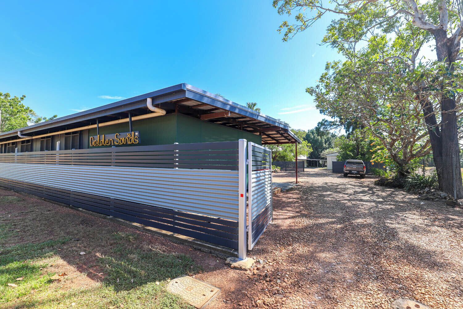 A building with a metal exterior and a covered area, possibly a garage or workshop, with a sign that reads 'Golden Sounds.'
