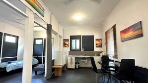 A compact room with a kitchenette, a dining area, and two single beds.