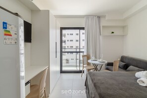 Habitación de hotel moderna con cama, escritorio, silla, una mesita y un balcón con vistas a la ciudad.