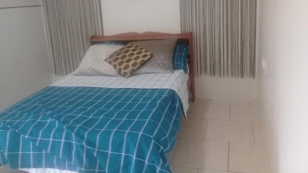 Una cama con colcha a cuadros, un cojín estampado con jirafas y una obra de arte circular colgada en la pared.
