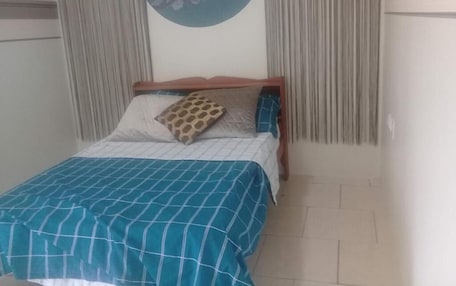 A bed with a checkered bedspread, a pillow with a giraffe pattern, and a wall-mounted circular artwork.