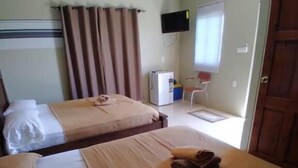 Una habitación de hotel con dos camas, televisión, escritorio y puerta.