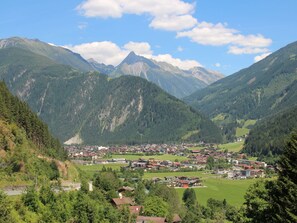 Eine gebirgige Landschaft mit einem Talgrund und einer Stadt, umgeben von üppiger Vegetation und Bergen.