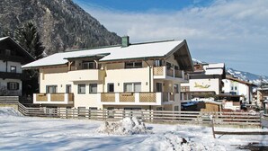 Ein mehrstöckiges Hotel mit verschneitem Dach, hölzernen Balkonen und einer Bergkulisse.