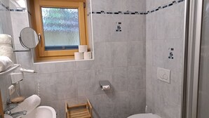 Ein kleines Badezimmer mit Toilette, Waschbecken und einem kleinen Fenster.