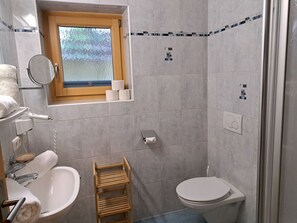 Ein kleines Badezimmer mit Toilette, Waschbecken und einem kleinen Fenster.