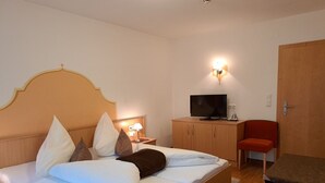 Ein Hotelzimmer mit Bett, Fernseher, Schreibtisch und Stuhl.