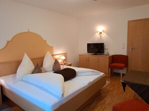 Ein Hotelzimmer mit Bett, Fernseher, Schreibtisch und Stuhl.