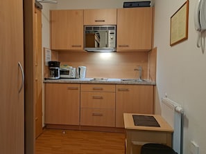Eine kleine Küchenzeile mit Mikrowelle, Toaster, Kaffeemaschine und Spüle.
