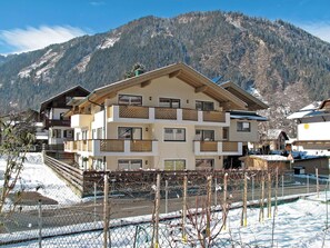 Ein mehrstöckiges Hotel mit Balkonen vor einer Bergkulisse.