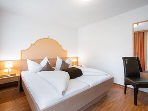 Ein ordentlich gemachtes Bett mit weißer und brauner Bettwäsche, einem Holz-Kopfteil und zwei Nachttischlampen.