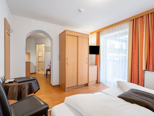 Ein Hotelzimmer mit Bett, Schreibtisch, Stuhl, Kleiderschrank und Fernseher.