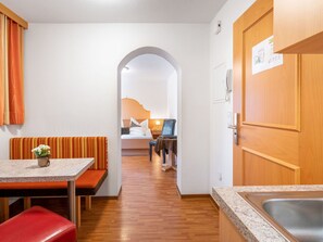 Ein Hotelzimmer mit einer Küchenzeile, einem Essbereich mit einer Bank und einem Bett mit einem Nachttisch.