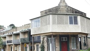 Un edificio ad angolo con una porta rossa, un balcone e una panchina all'esterno.